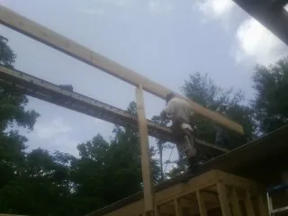 Carpenter setting a ridge beam over a new addition frame — Ice Dam Removal by Roofing Brothers in Aledo